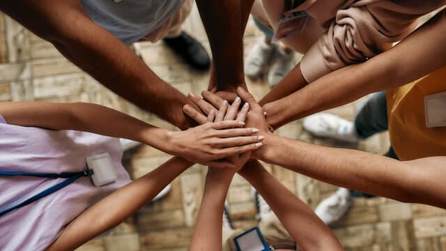 A group stacking hands together in a huddle